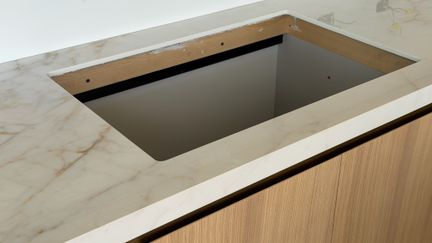 A finished undermount sink cutout in an installed marble countertop, the stone edge running an even reveal around all four sides of the steel basin.